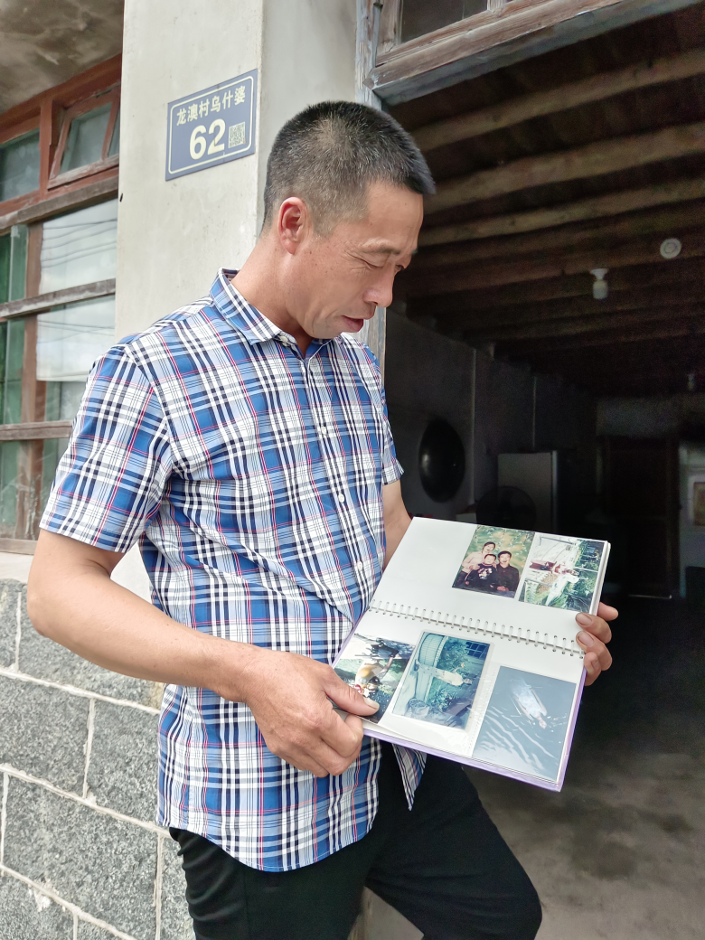 温作喜向记者展示儿子小时候照片，介绍儿子成长轨迹.jpg